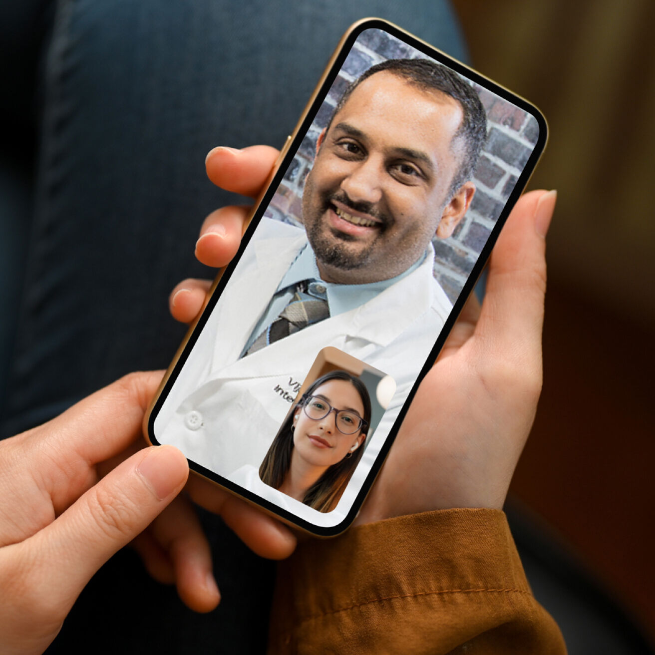 A person holds a smartphone displaying a video call with a doctor wearing a white coat.